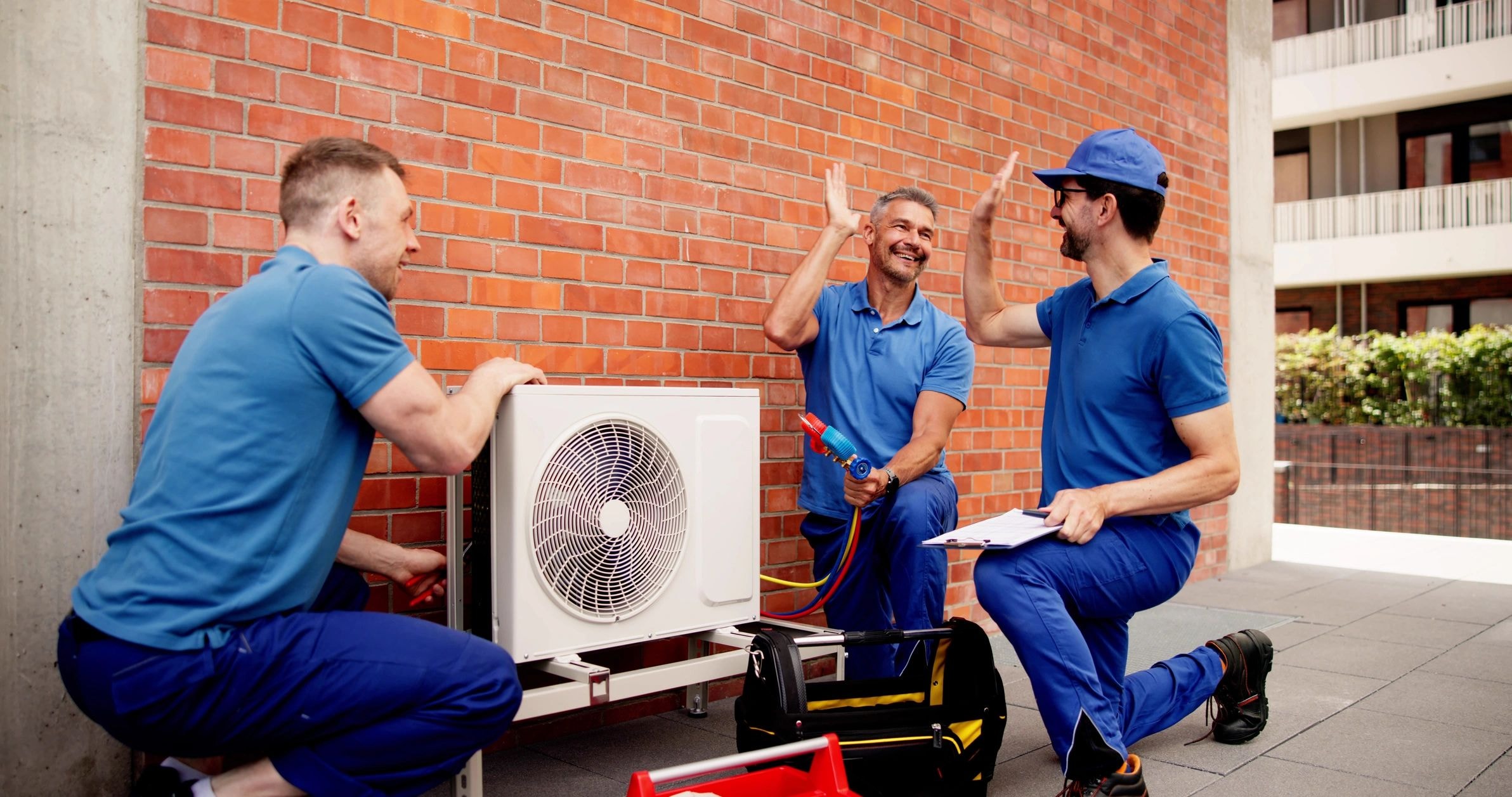 Three HVAC technicians collaborating on equipment